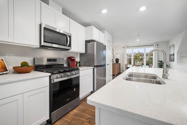 kitchen with appliances with stainless steel finishes, dark hardwood / wood-style floors, white cabinetry, sink, and light stone countertops