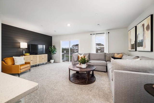 carpeted living room with wood walls