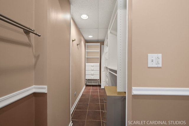 interior space with a drop ceiling and dark tile patterned flooring