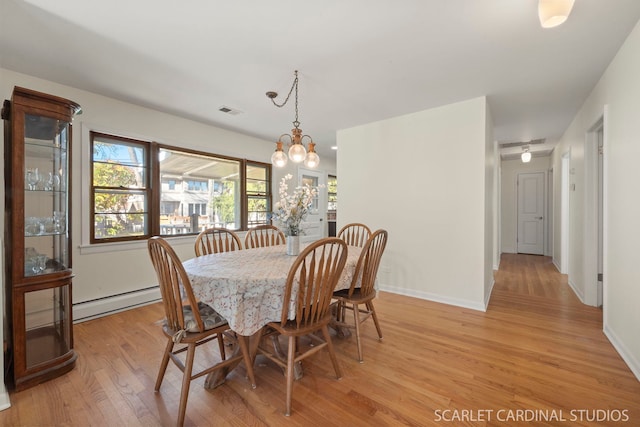 dining area with a notable chandelier, light hardwood / wood-style floors, and a baseboard heating unit