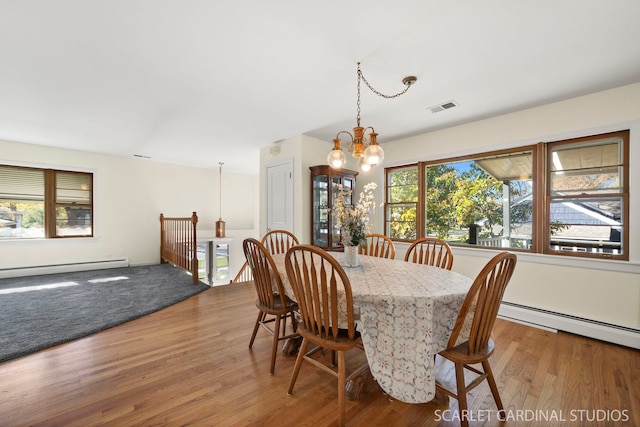 dining space with an inviting chandelier, a wealth of natural light, wood-type flooring, and baseboard heating