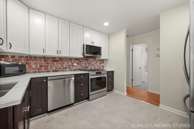 kitchen featuring appliances with stainless steel finishes, white cabinetry, backsplash, dark brown cabinetry, and light tile patterned flooring