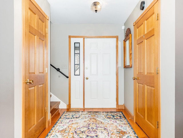 foyer with stairway, light wood-style flooring, and baseboards