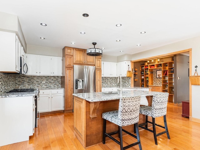 37W751 Orchard Ln, Elgin, IL 60124 - kitchen with appliances with stainless steel finishes, a kitchen breakfast bar, light stone countertops, a kitchen island with sink, and light wood-type flooring