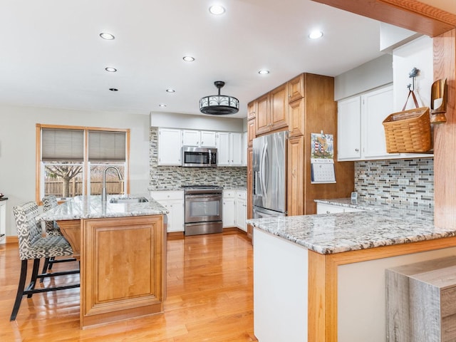 37W751 Orchard Ln, Elgin, IL 60124 - kitchen featuring appliances with stainless steel finishes, a sink, light wood-style flooring, and light stone countertops