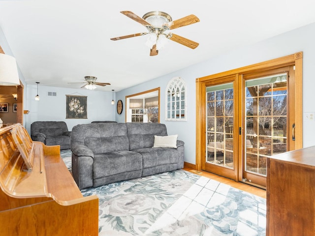 living area with ceiling fan, visible vents, and wood finished floors