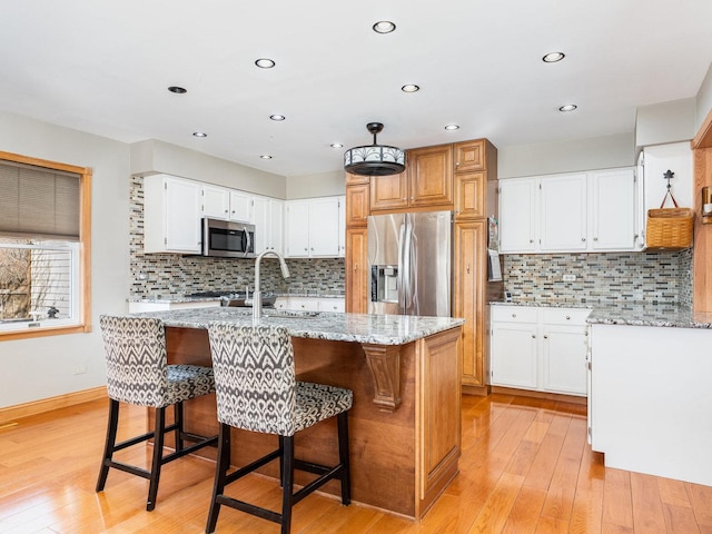 37W751 Orchard Ln, Elgin, IL 60124 - kitchen with light stone counters, light wood finished floors, appliances with stainless steel finishes, a sink, and an island with sink