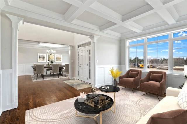 living room with coffered ceiling, ornate columns, a notable chandelier, beam ceiling, and hardwood / wood-style floors