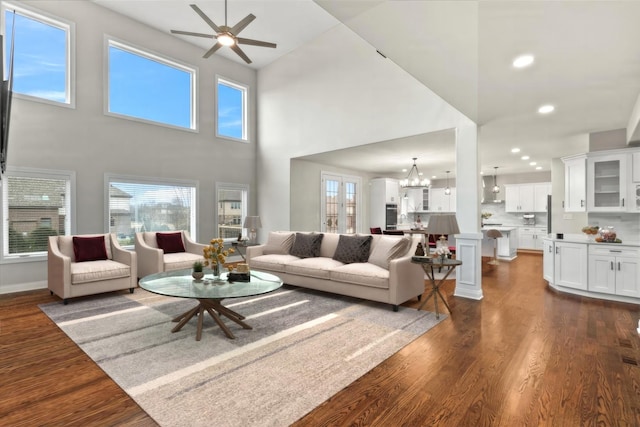 living room featuring dark wood-type flooring and ceiling fan with notable chandelier