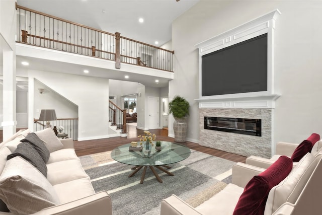 living room featuring hardwood / wood-style flooring, a fireplace, and a high ceiling