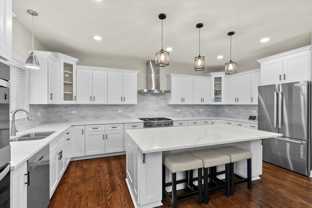 kitchen featuring white cabinets, stainless steel appliances, sink, and wall chimney range hood