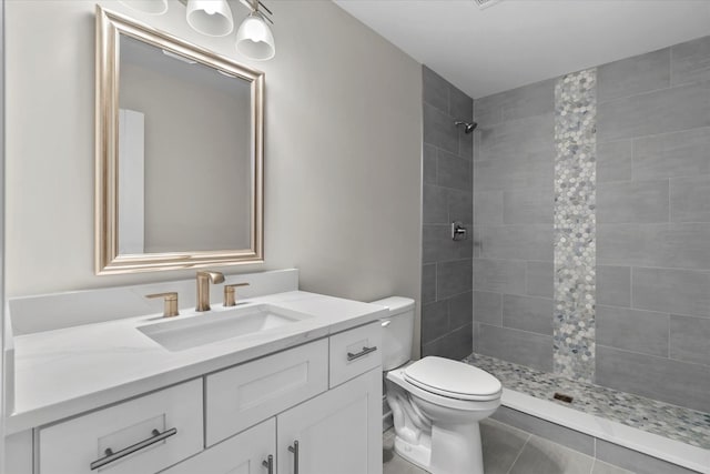 bathroom with vanity, toilet, and a tile shower