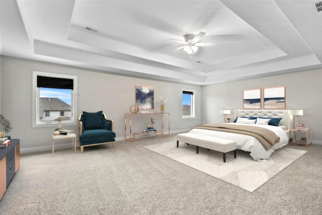 bedroom with a raised ceiling, ceiling fan, and carpet