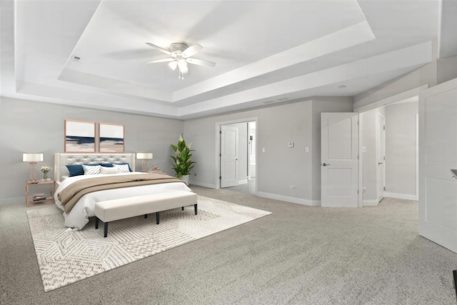 carpeted bedroom featuring a raised ceiling and ceiling fan