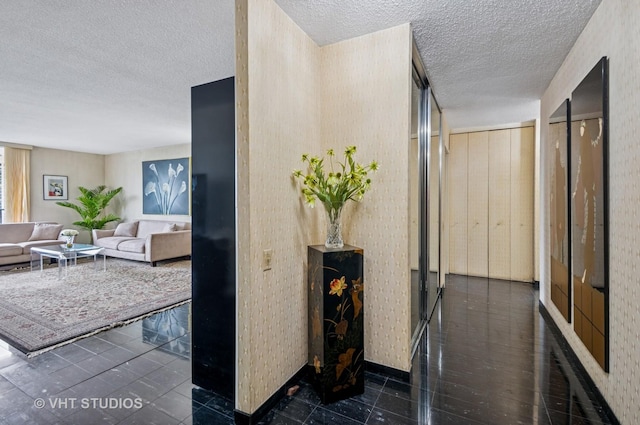 hallway with a textured ceiling, baseboards, and wallpapered walls