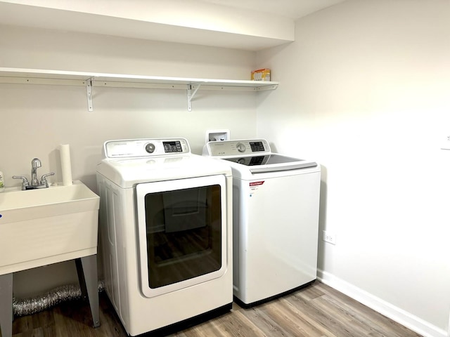 laundry room featuring separate washer and dryer, sink, and light wood-type flooring