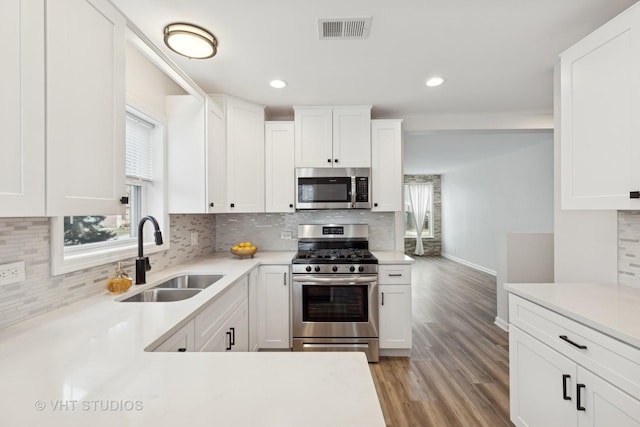 kitchen featuring stainless steel appliances, white cabinetry, sink, and light hardwood / wood-style flooring