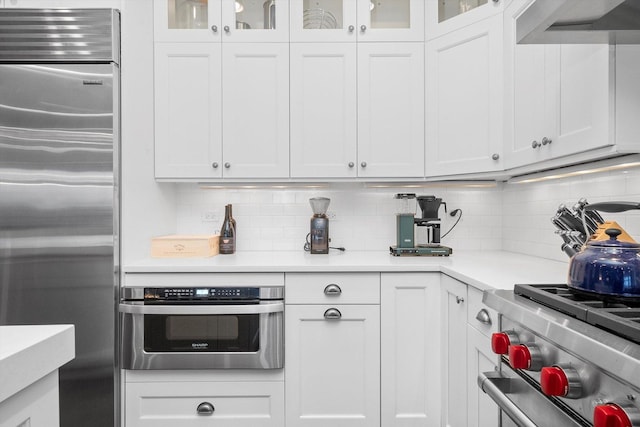 kitchen featuring white cabinetry, decorative backsplash, and premium appliances