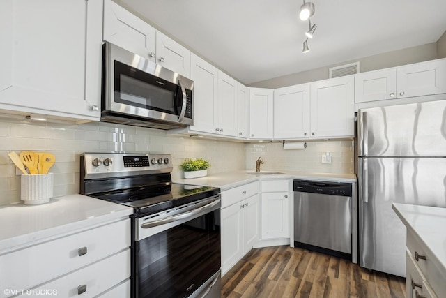 kitchen featuring sink, white cabinetry, appliances with stainless steel finishes, dark hardwood / wood-style floors, and decorative backsplash