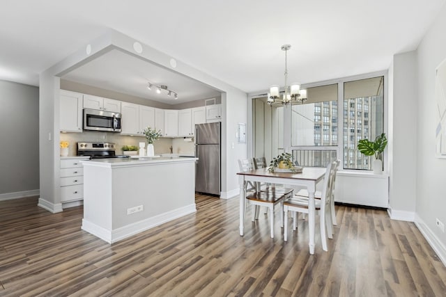 kitchen featuring a center island, dark hardwood / wood-style floors, pendant lighting, stainless steel appliances, and white cabinets