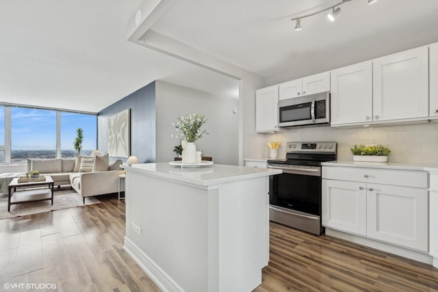 kitchen featuring decorative backsplash, stainless steel appliances, white cabinets, and hardwood / wood-style flooring