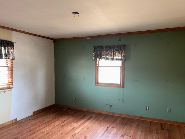 empty room featuring ornamental molding and light wood-type flooring