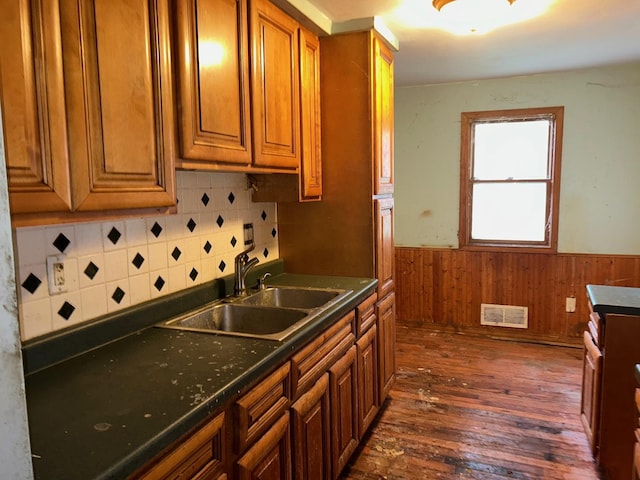 kitchen featuring sink, backsplash, dark hardwood / wood-style floors, and wood walls