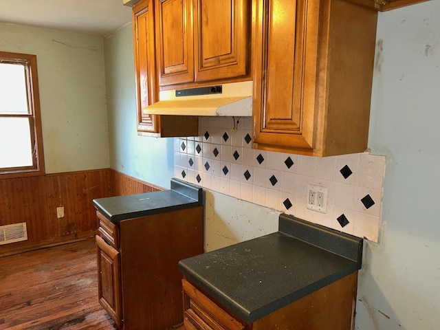 kitchen featuring backsplash, dark wood-type flooring, and wooden walls