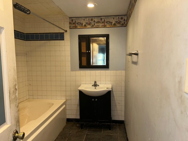 bathroom with tile patterned flooring, vanity, tiled shower / bath combo, and tile walls