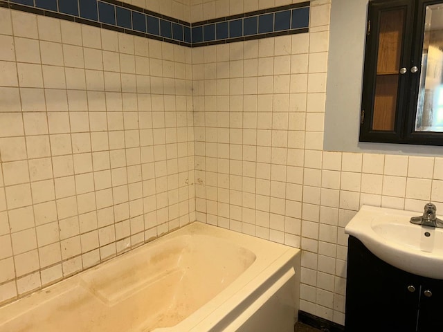 bathroom with a tub to relax in, vanity, and tile walls