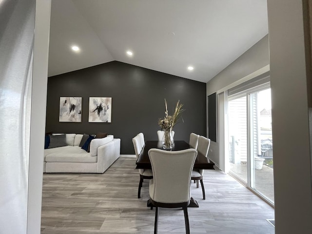 dining area featuring vaulted ceiling and light hardwood / wood-style flooring