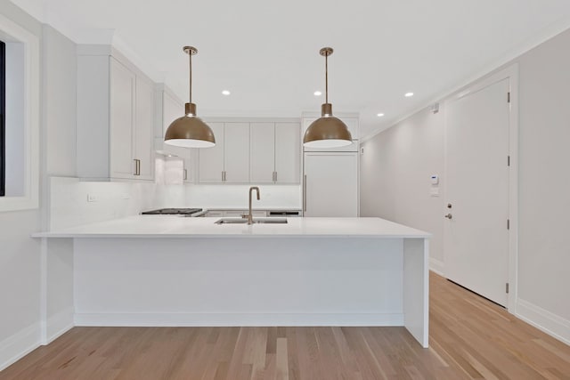 kitchen with white cabinetry, sink, decorative light fixtures, and kitchen peninsula