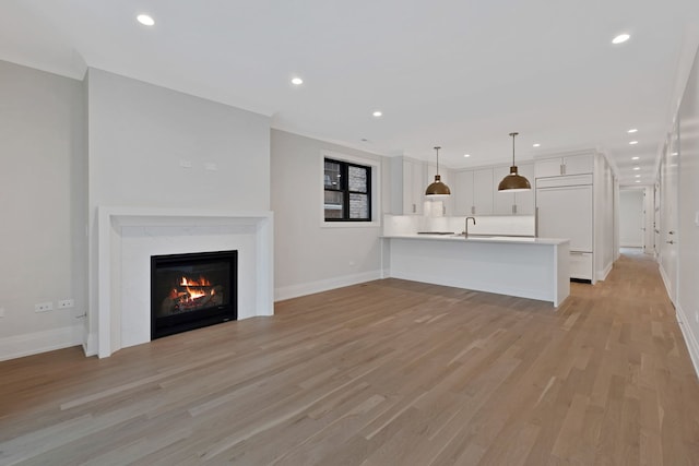 unfurnished living room with sink, a fireplace, and light wood-type flooring