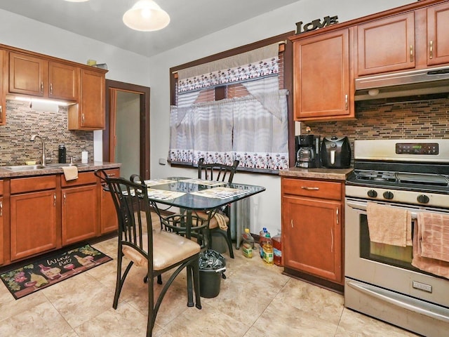 kitchen featuring stainless steel gas range oven, sink, and backsplash