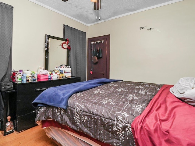 bedroom with crown molding, hardwood / wood-style floors, ceiling fan, and a textured ceiling