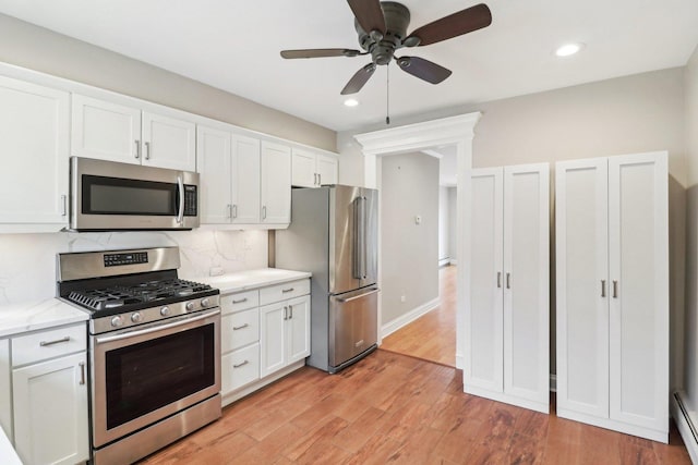 kitchen featuring stainless steel appliances, white cabinetry, tasteful backsplash, and light wood-type flooring