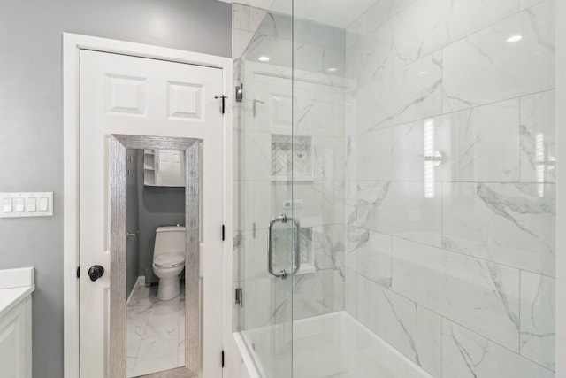 bathroom featuring vanity, toilet, and a shower with shower door