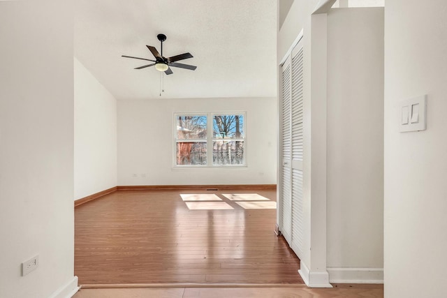 empty room featuring ceiling fan, a textured ceiling, wood finished floors, and baseboards