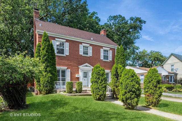 colonial-style house featuring a front yard and central AC unit