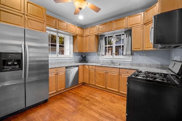 kitchen featuring sink, light hardwood / wood-style flooring, ceiling fan, appliances with stainless steel finishes, and light stone countertops