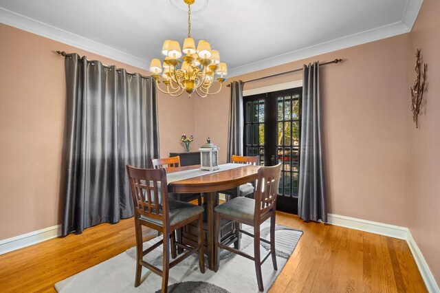 dining area with a notable chandelier, ornamental molding, light hardwood / wood-style floors, and french doors