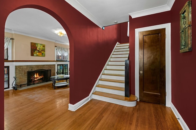 staircase featuring hardwood / wood-style flooring, ornamental molding, and a fireplace