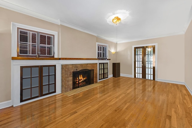 unfurnished living room with a brick fireplace, hardwood / wood-style flooring, ornamental molding, and french doors