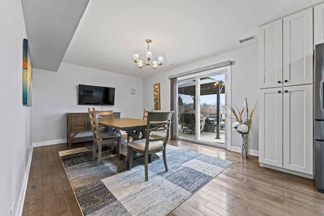 dining space with a notable chandelier and light hardwood / wood-style flooring