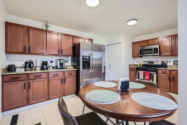 kitchen featuring light tile patterned floors, visible vents, stainless steel appliances, and light stone counters