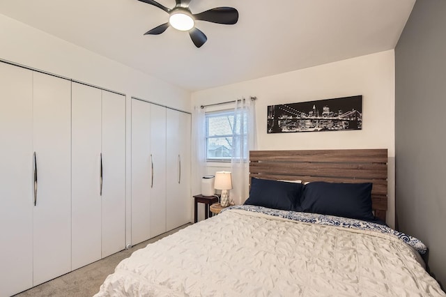 carpeted bedroom featuring ceiling fan and two closets