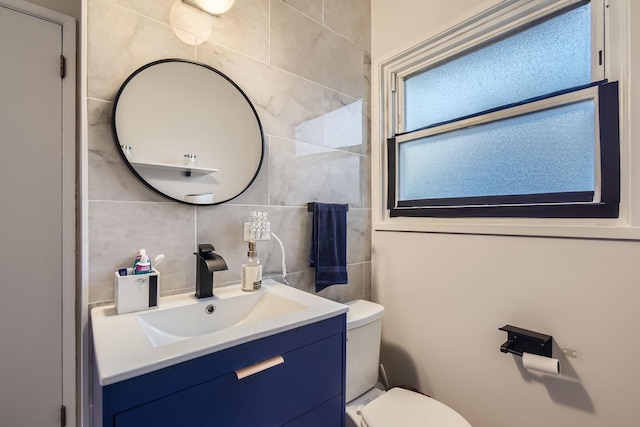 bathroom with tasteful backsplash, tile walls, vanity, and toilet