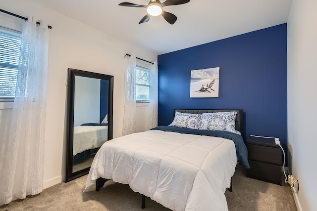 carpeted bedroom with ceiling fan and baseboards