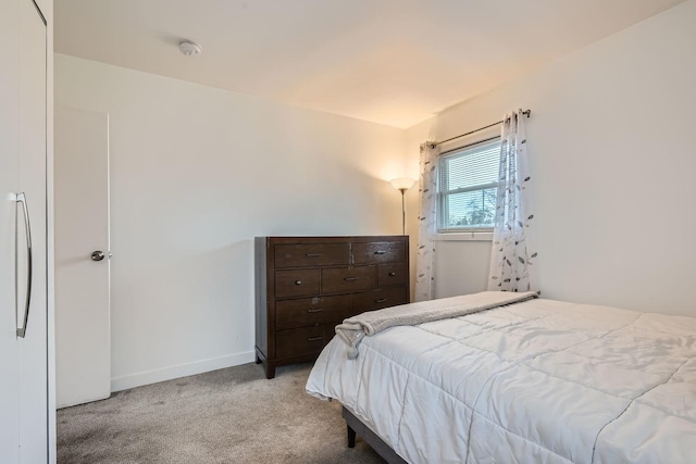 carpeted bedroom with freestanding refrigerator and baseboards