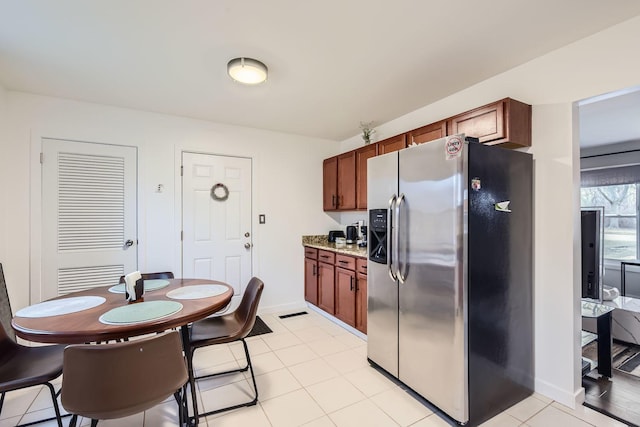 kitchen with light tile patterned floors, baseboards, light stone counters, and stainless steel fridge with ice dispenser